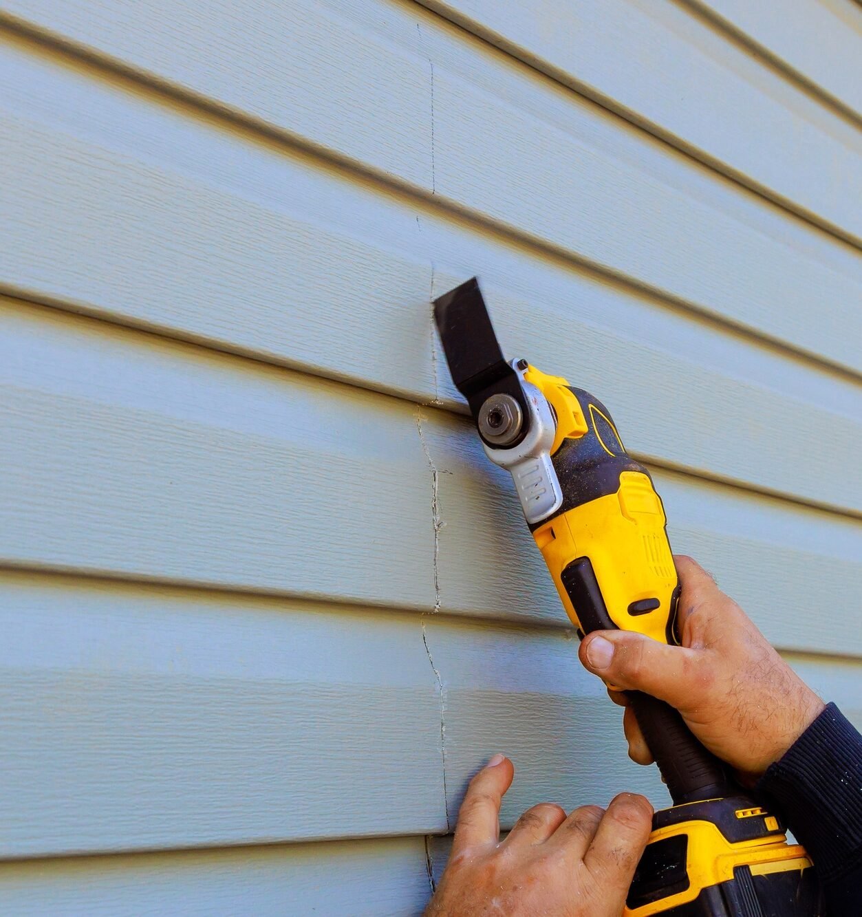 As part of reconstruction of house, a multi tool is used to remove damaged vinyl siding